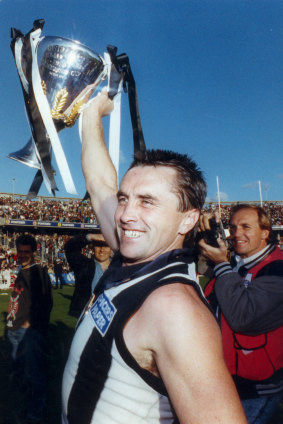 Former Collingwood captain Tony Shaw holds up the 1990 premiership cup. He later coached now Carlton CEO Cain Liddle for a short period at the Magpies.