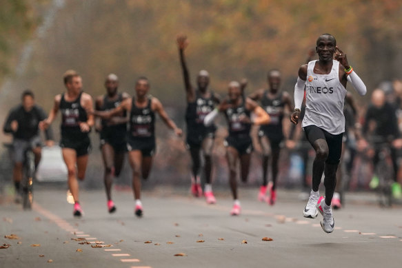 Eliud Kipchoge approaches the finish line after running 1:159 in a marathon in 2019, with his pacemakers celebrating behind. 