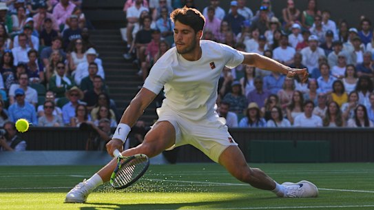 Defending two-time Wimbledon champion Carlos Alcaraz slides to return serve against Cameron Norrie.