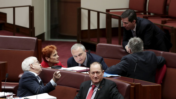 Education Minister Simon Birmingham, right, talks with members of the crossbench.