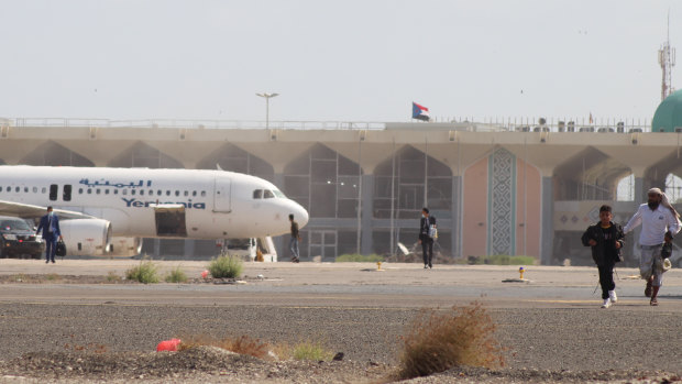 People walk away from the runway following an explosion at the airport in Aden, Yemen.