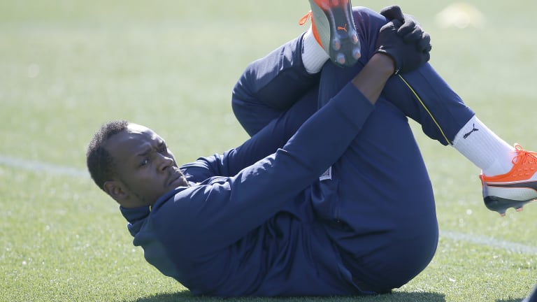 Full stretch: Bolt warms up before his first training session with the Mariners on Tuesday. 