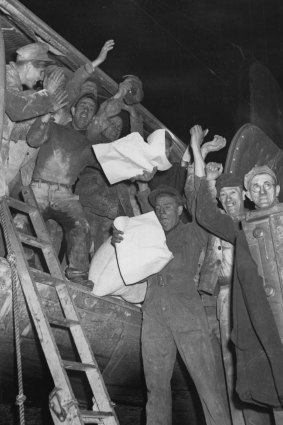 Airlift cargo workers cheer as they read of the blockade lifting in a Berlin newspaper. 