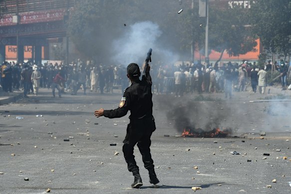 A police officer fires a tear gas shell to disperse angry Shiite Muslims during a protest to condemn the killing of Iranian Supreme Leader Ayatollah Ali Khamenei.