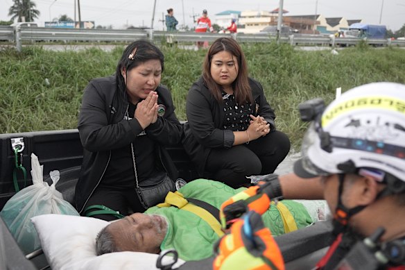 Krongkarn Jantarasavad (left) praying over her father – 76-year-old Damrong Chantarawasat – who  missed dialysis treatment because floods had trapped him inside the family home.