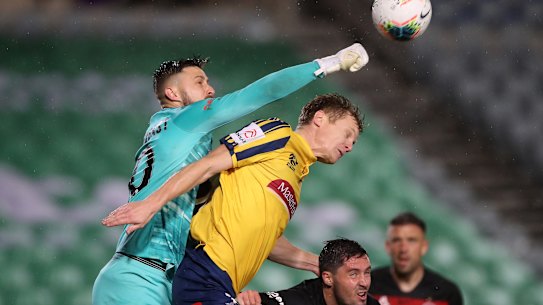 Wanderers keeper Tristan punches the ball away from Matt Simon of the Mariners.