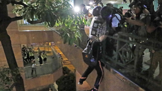 A protester hangs from a bridge as police officers try to pull him up after a scuffle with police.