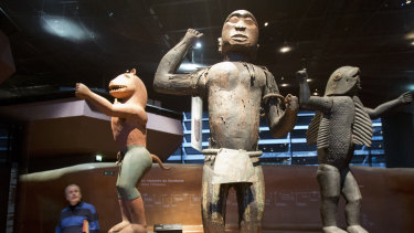 A visitor look at wooden royal statues of the Dahomey kingdom at Quai Branly museum in Paris.