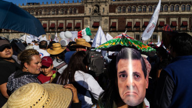 An attendee wears a mask in the likeness of a frowning Enrique Pena Nieto, Mexico's former president, during Obrador's inauguration.
