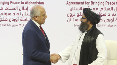 US peace envoy Zalmay Khalilzad, left, and the Taliban’s Mullah Abdul Ghani Baradar shake hands after signing a peace agreement in Doha, Qatar in February 2020.