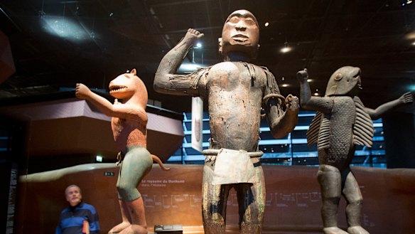 A visitor look at wooden royal statues of the Dahomey kingdom at Quai Branly museum in Paris.