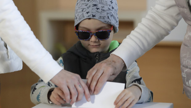 A child assists his relatives their votes at a polling station during the second round of the presidential election in Bratislava, Slovakia, on Saturday, March 30.