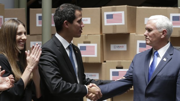 Venezuela's self-proclaimed interim president Juan Guaido, centre, shakes hands with US Vice-President Mike Pence in a room filled with humanitarian aid in Bogota, Colombia. Guaido's wife Fabiana Rosales is pictured left.