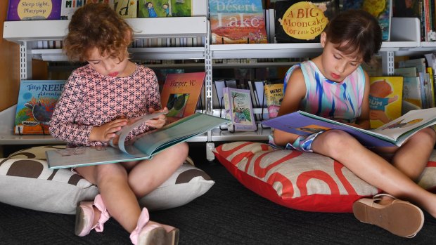 The Leong sisters - Olivia, 4, and Isabelle, 7 - read books in the tiny children’s section of the State Library of NSW. Planning for a new dedicated children's library is under way.
 