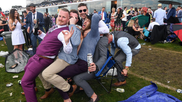 Race fans enjoy the last moments of a muddy Melbourne Cup day.