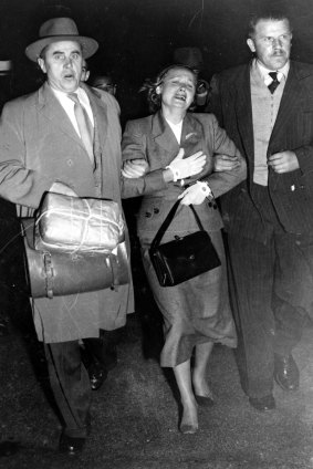 Two Soviet officials escort Evdokia Petrov towards a plane at Mascot Airport.