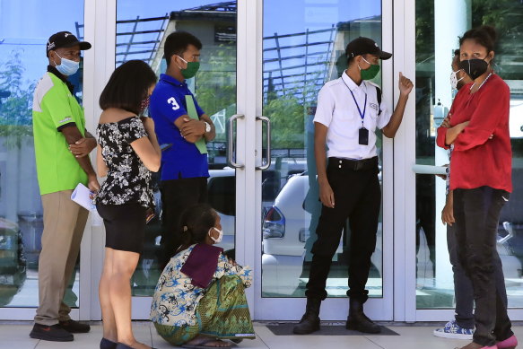 People wearing protective face masks queue to enter a shopping center in Dili, East Timor last week. 