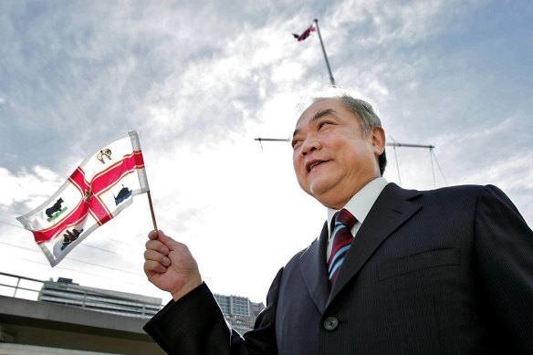 Former lord mayor John So waves a Melbourne flag for Melbourne Day in 2008. 