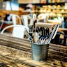 A warm cafe interior with wooden table, cutlery, pot plant and food counter in the background Generic cafe restaurant
iStock