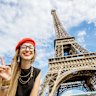 Woman tourist posing at Eiffel Tower, Paris in beret.