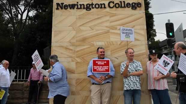 Former students and parents of students at Newington College holding protest signs at the entrance of the private boys college. 
