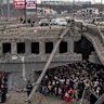 Ukrainians crowd under a destroyed bridge as they try to flee across the Irpin River in the outskirts of Kyiv, Ukraine on Saturday.
