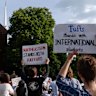 Demonstrators hold signs during a protest in support of international students at Harvard University.
