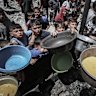 Displaced Palestinians collect cooked food from a community food kitchen in Jabaliya, northern Gaza, on Monday, May 19, 2025.