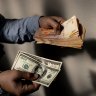 A money changer holds US hundred-dollar banknotes and 1000-peso banknotes in Buenos Aires, Argentina.