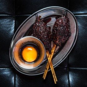 Duck meatball skewers served with egg yolk and tare vinegar.