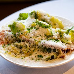 Caesar salad is mixed at the table. 