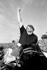John Madden is carried off the field after training the Raiders for the 1977 Super Bowl trophy.