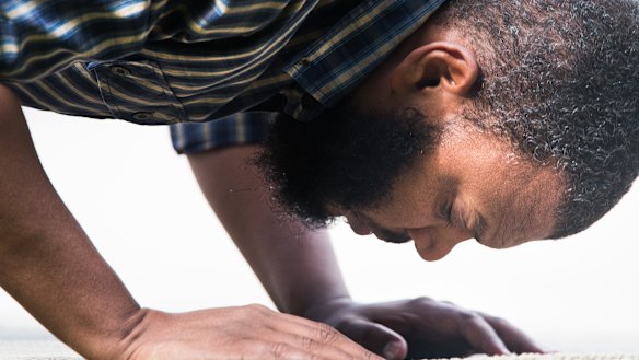 A man in prays in Hagley Park.