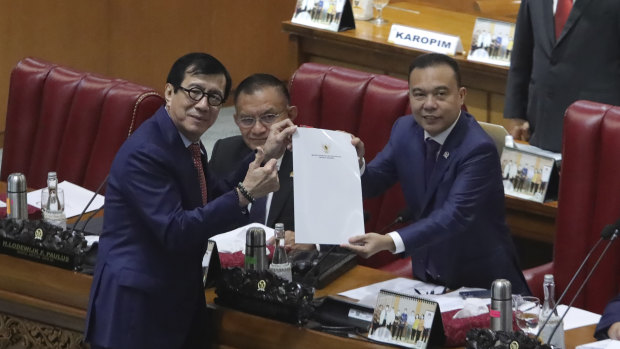 Law and Human Rights Minister Yasonna Laoly, left, poses for photos after the passage of the new criminal code through Indonesian parliament.