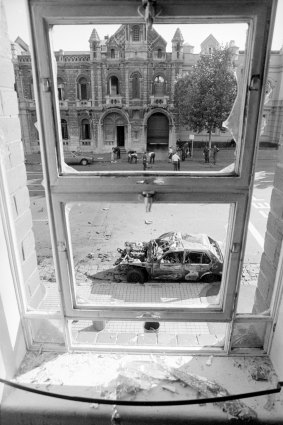 Russell Street bombing: A shattered first-floor window frames one of the burnt-out cars on Russell Street.