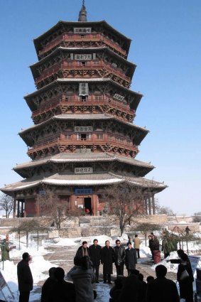 Turistler, 2003 yılında Çin'in kuzeyindeki Shanxi Eyaletinin Yingxian İlçesinde kısmen karla kaplı antik ahşap pagodanın önünde fotoğraf çekiyor.  