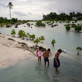 Children wade through water at high tide in the village of Abarao on the Pacific nation of Kiribati, one of the countries most vulnerable to climate change.