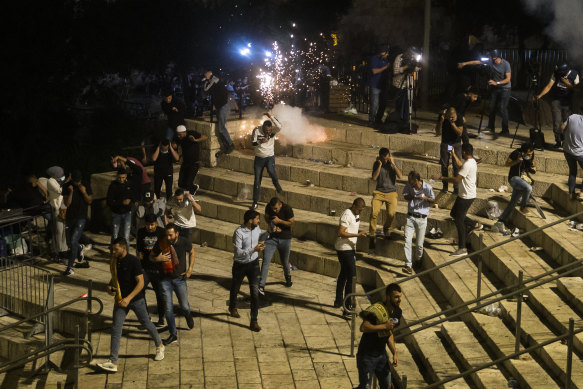 Palestinians escape from a stun grenade fired by Israeli police officers during clashes at Damascus Gate during Ramadan in Israeli-occupied East Jerusalem on May 8, 2021. 
