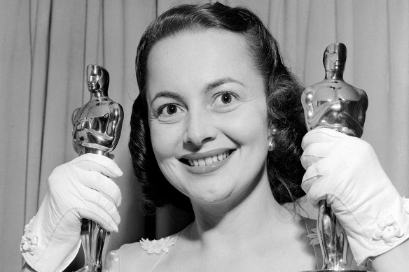 Olivia de Havilland holds two Oscars as she returns home following the Academy Awards presentation in 1950.