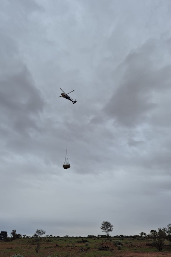 A military Blackhawk carrying hay in a sling arrives at Joe and Stacy Tully’s property in western Queensland.