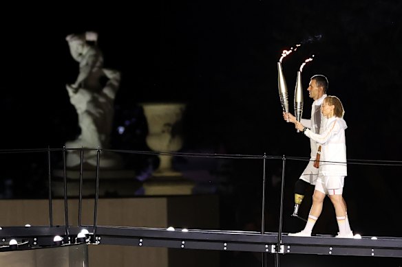 Torchbearers Alexis Hanquinquant and Nantenin Keita of Team France carry the Paralympic flames as they prepare to light the Olympic cauldron.