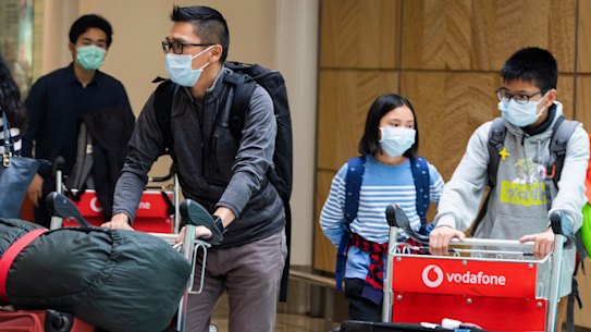 Passengers arrive at Sydney Airport on Monday wearing masks.