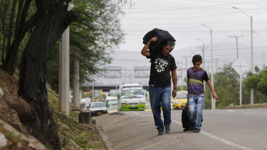 Venezuelan father Darwin Zapata walks with his 12-year-old son, as they make their way to Peru. 