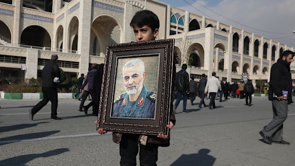 A boy carries a portrait of Iranian Revolutionary Guard Gen. Qassem Soleimani, who was killed in a U.S. airstrike in Iraq.