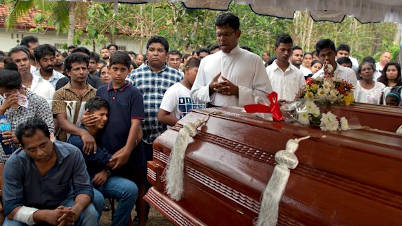 Dimitra Silva, fourth from left in blue, mourns the death of his brother, 13-year-old Anos Silva, and his grandparents, all of whom died at St Sebastian's Church.