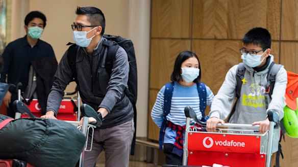 Passengers arrive at Sydney Airport on Monday wearing masks to avoid contact with the virus. 