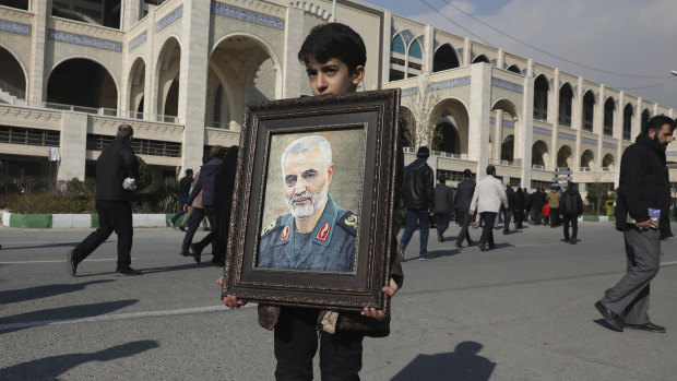 A boy carries a portrait of Iranian Revolutionary Guard Gen. Qassem Soleimani, who was killed in a U.S. airstrike in Iraq.