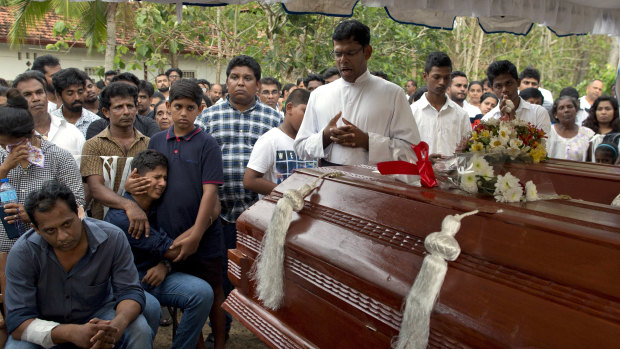 Dimitra Silva, fourth from left in blue, mourns the death of his brother, 13-year-old Anos Silva, and his grandparents, all of whom died at St Sebastian's Church.