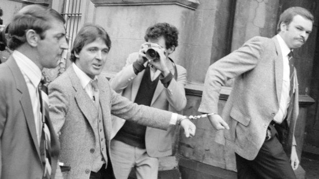 October 1981: Christopher Dale Flannery (second from left) is led handcuffed into Melbourne's City Watch House to be charged with the murder of Roger Wilson.