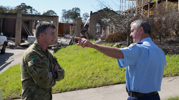 Assistant Commissioner Mick Willing and Brigadier Mick Garraway discuss clean-up measures at a bushfire-ravaged town.